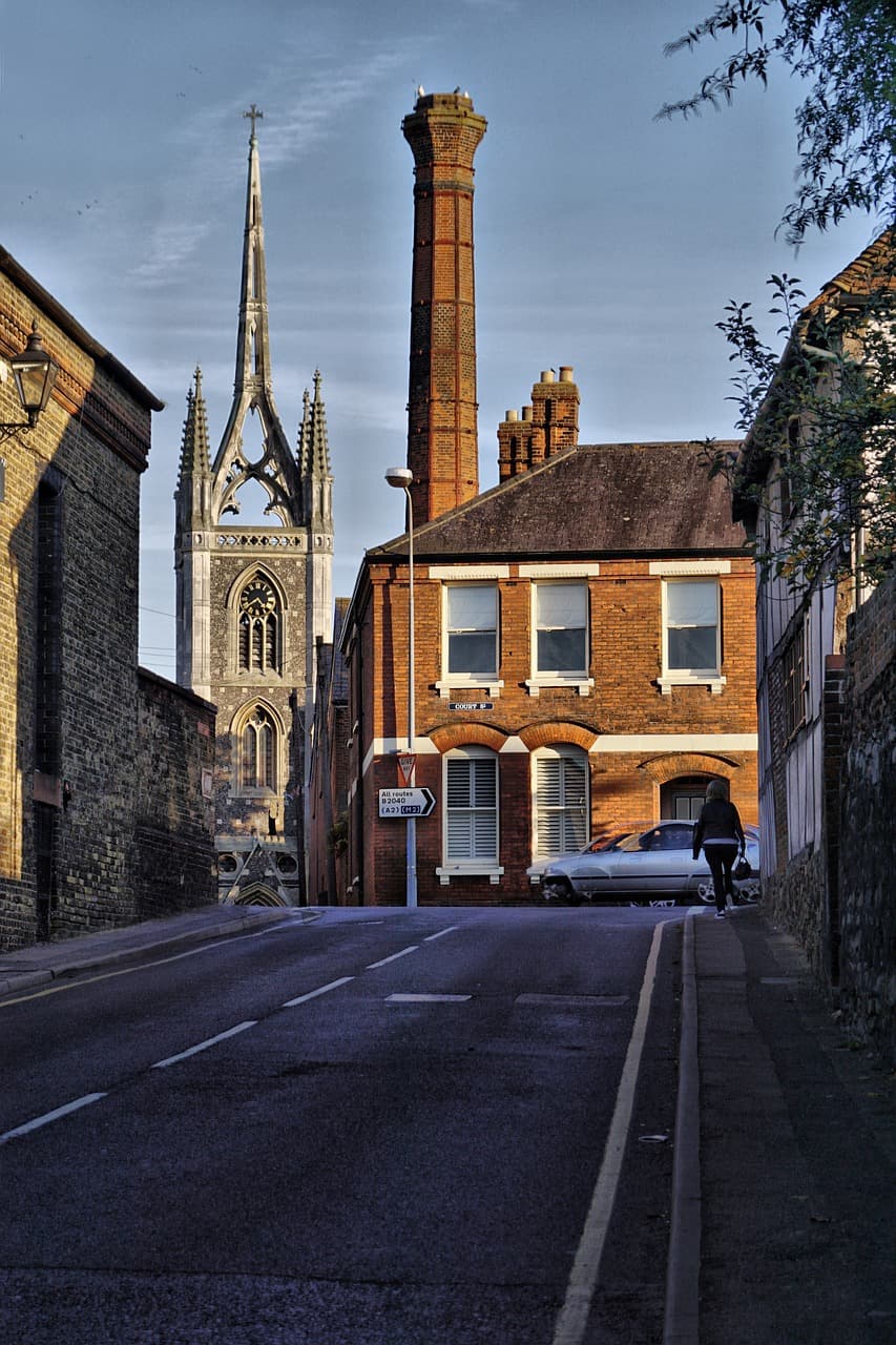 A Faversham street scene with the parish church spire and brick brewery chimney behind the rooftops
